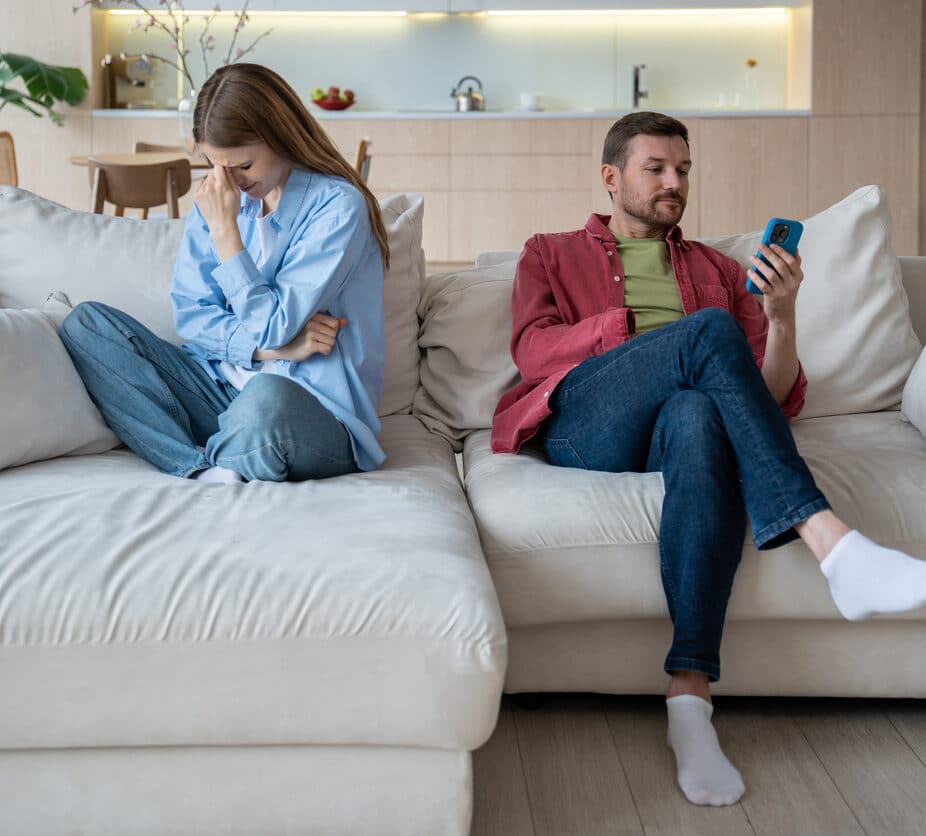 upset woman in stress crying, thinking of divorce. Indifferent husband addicted to mobile phone playing games, scrolling internet social networks, looks into smartphone ignoring wife