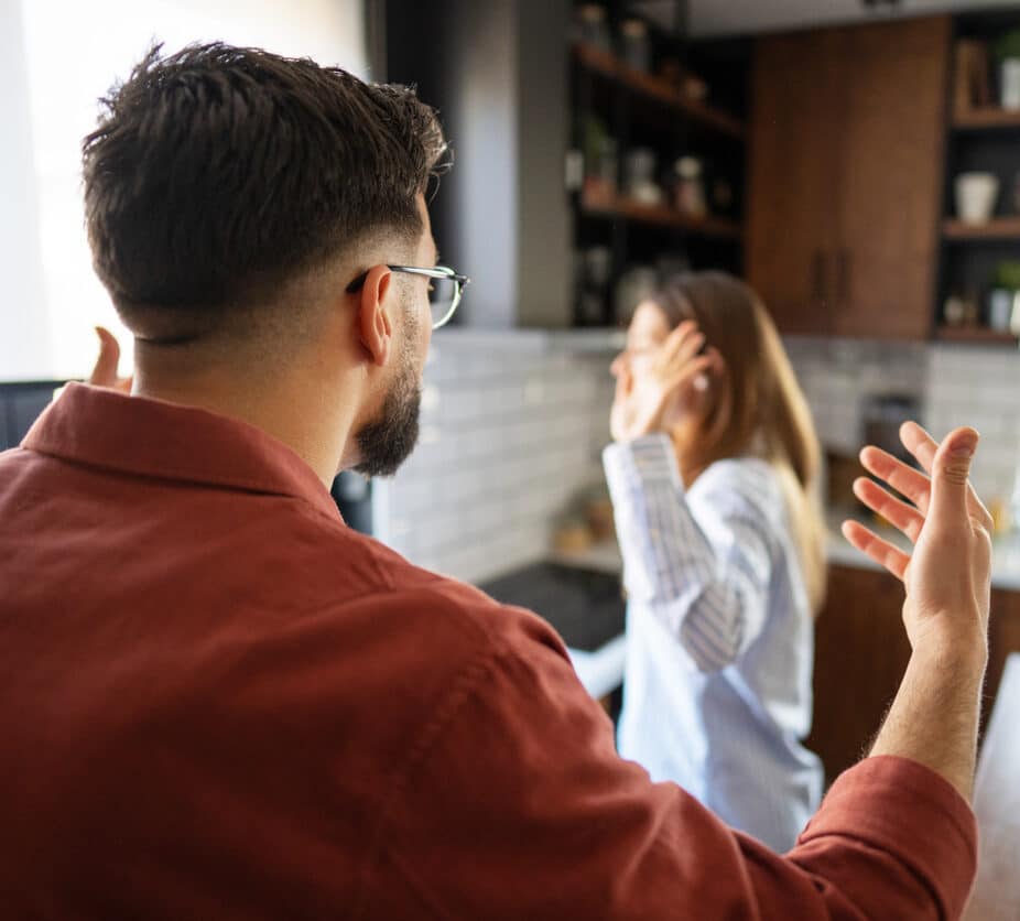 Man and woman in a modern kitchen having a tense, emotional argument, showing stress, frustration and a strained relationship during a serious domestic dispute